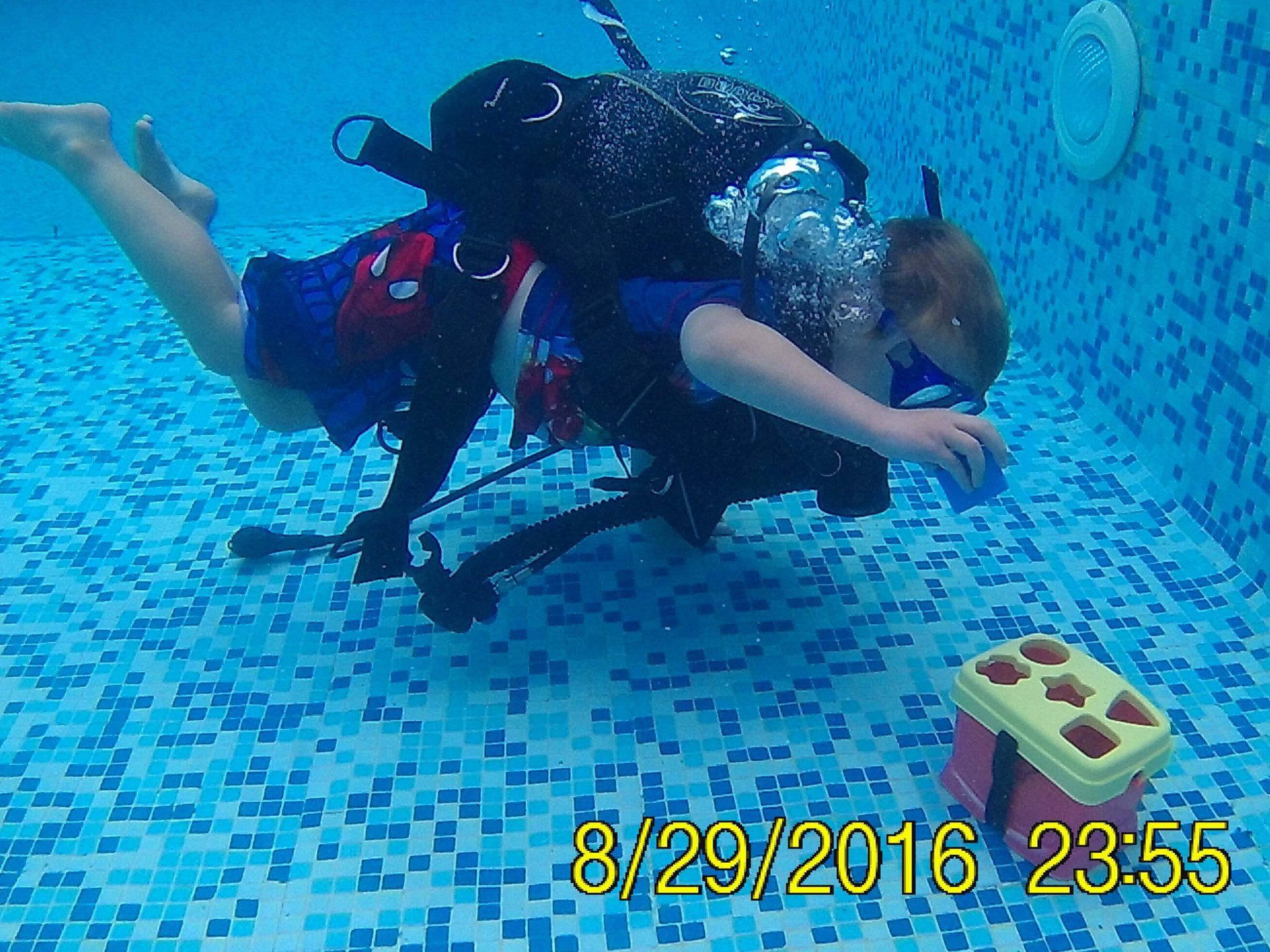 An underwater view of a child scuba diving placing a toy in a box