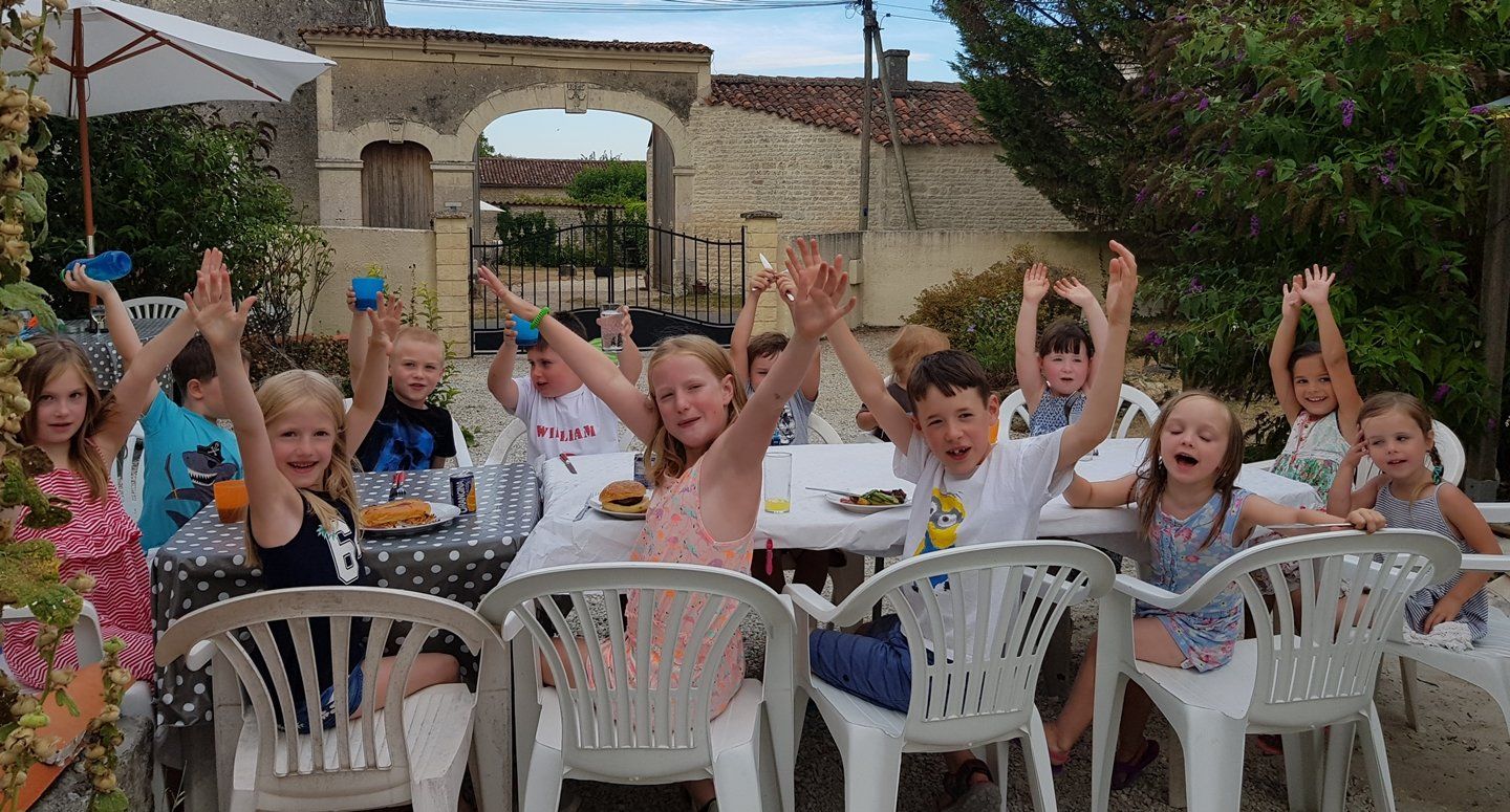 kinderen rond een tuintafel een bbq eten en plezier maken met zwaaien