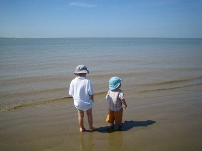 toddlers on a beach looking at the sea