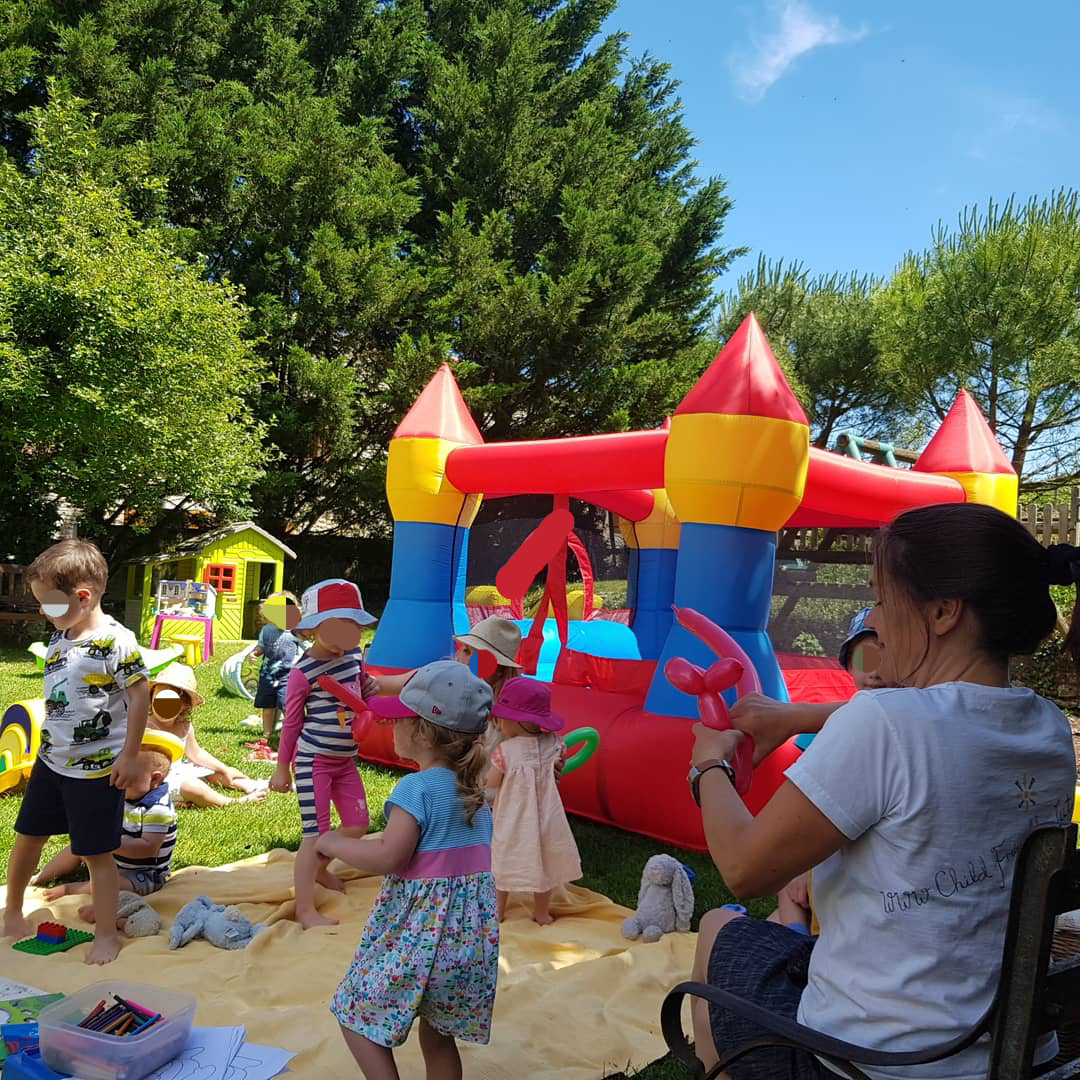 children playing next to a bouncy castle and a lady blowing up modelling balloons