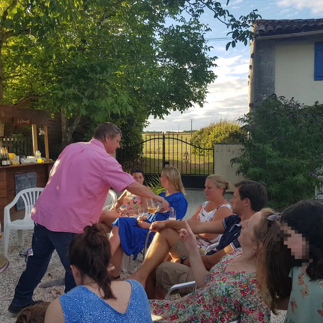 group of adults tasting wine around a table under a tree