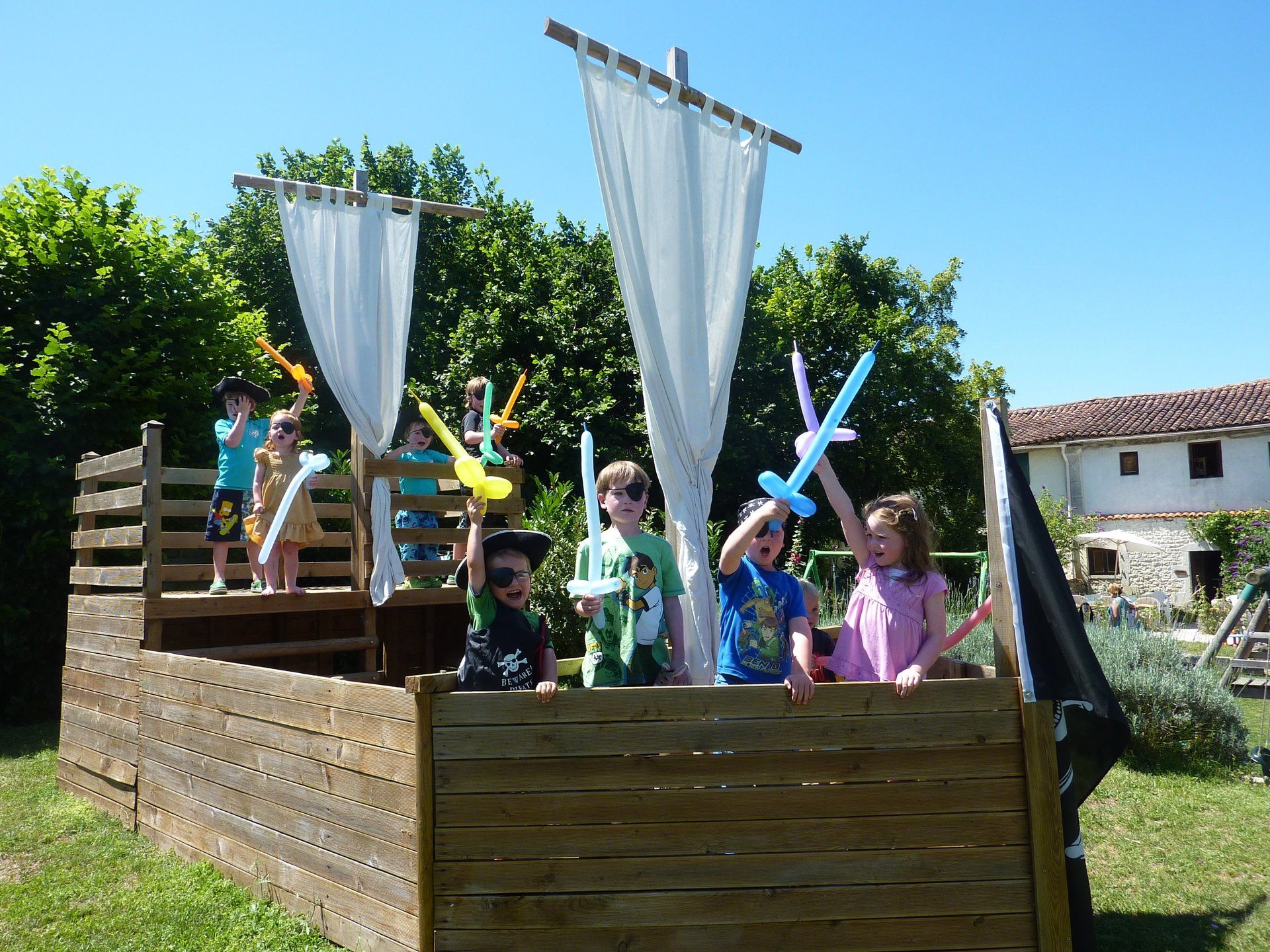 children waving balloon swords in a play pirate ship