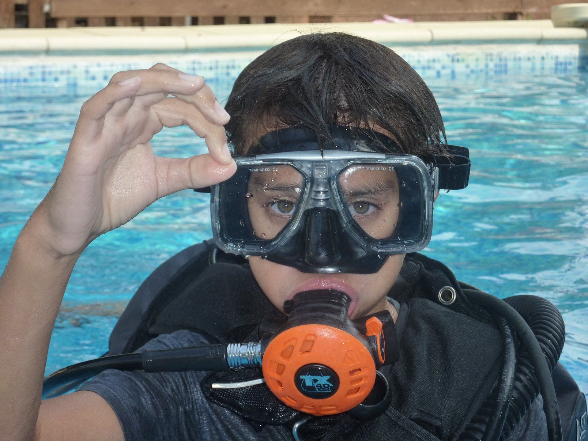 A child in scuba gear using their hands to say OK