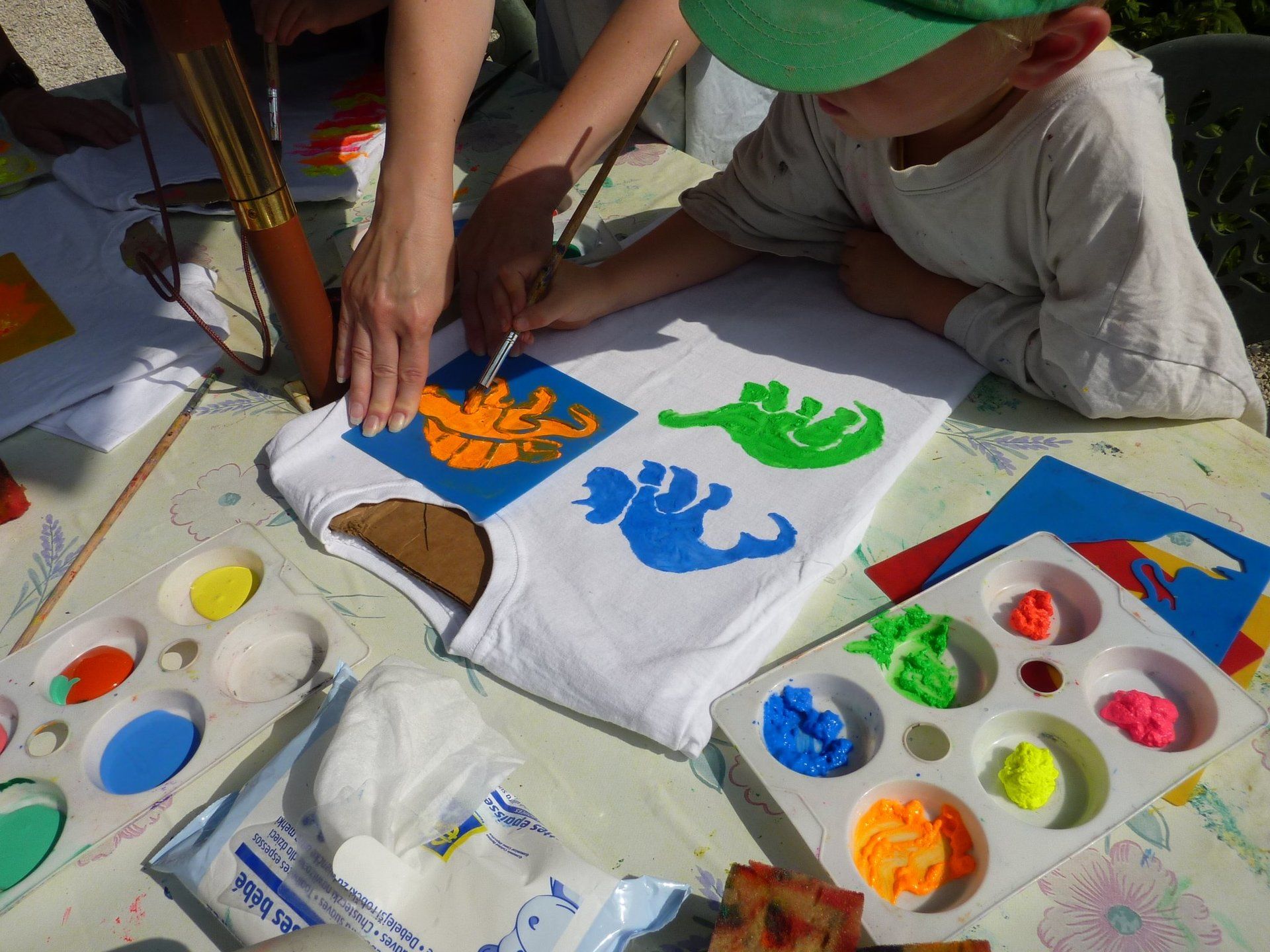 a child with green hat painting a t-shirt