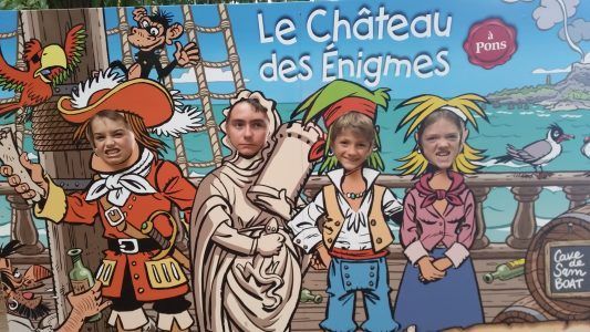 childrens faces peering through a pirate tableau at chateau des enigmas