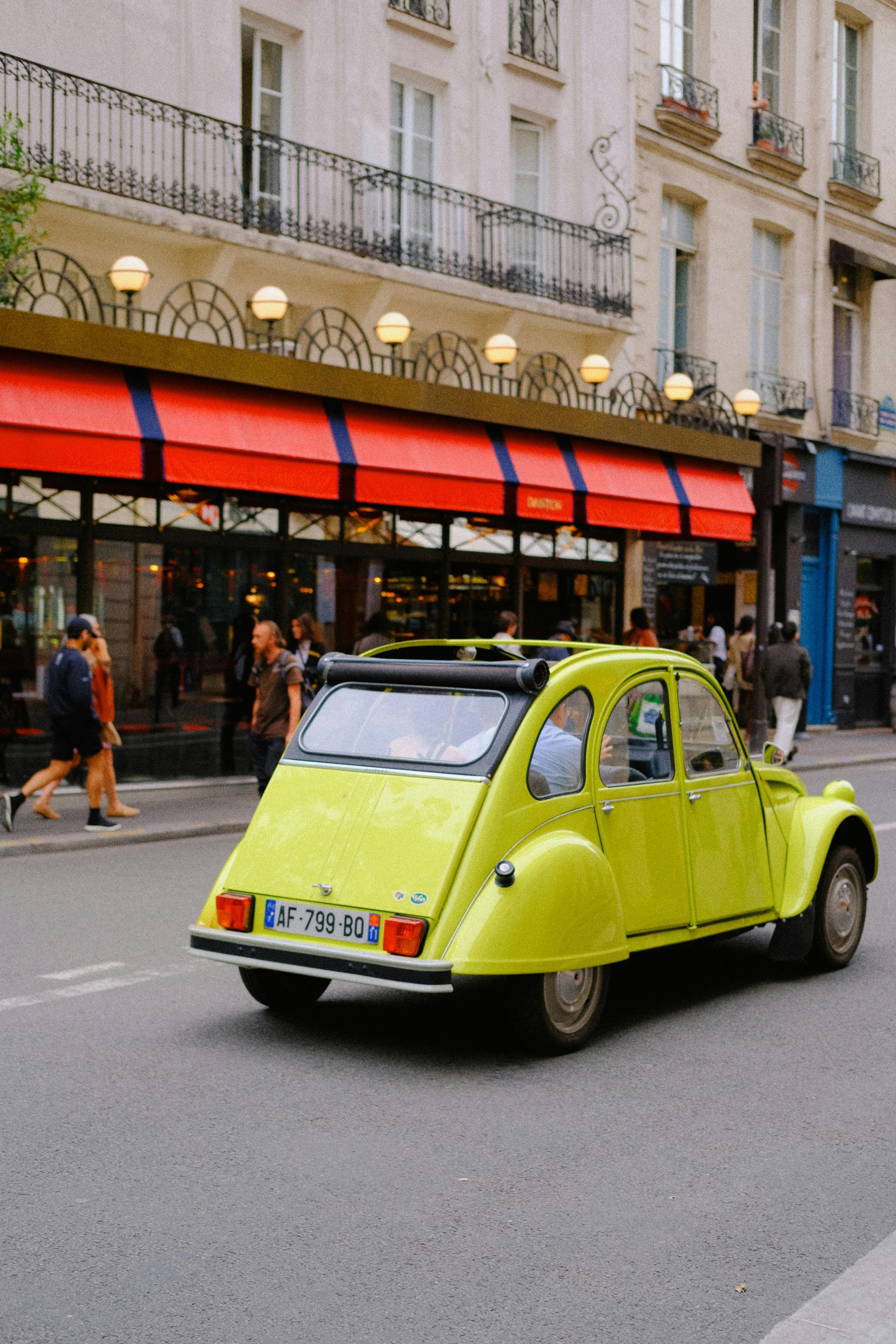 lime green Citroen  cv driving along a  French boulevard