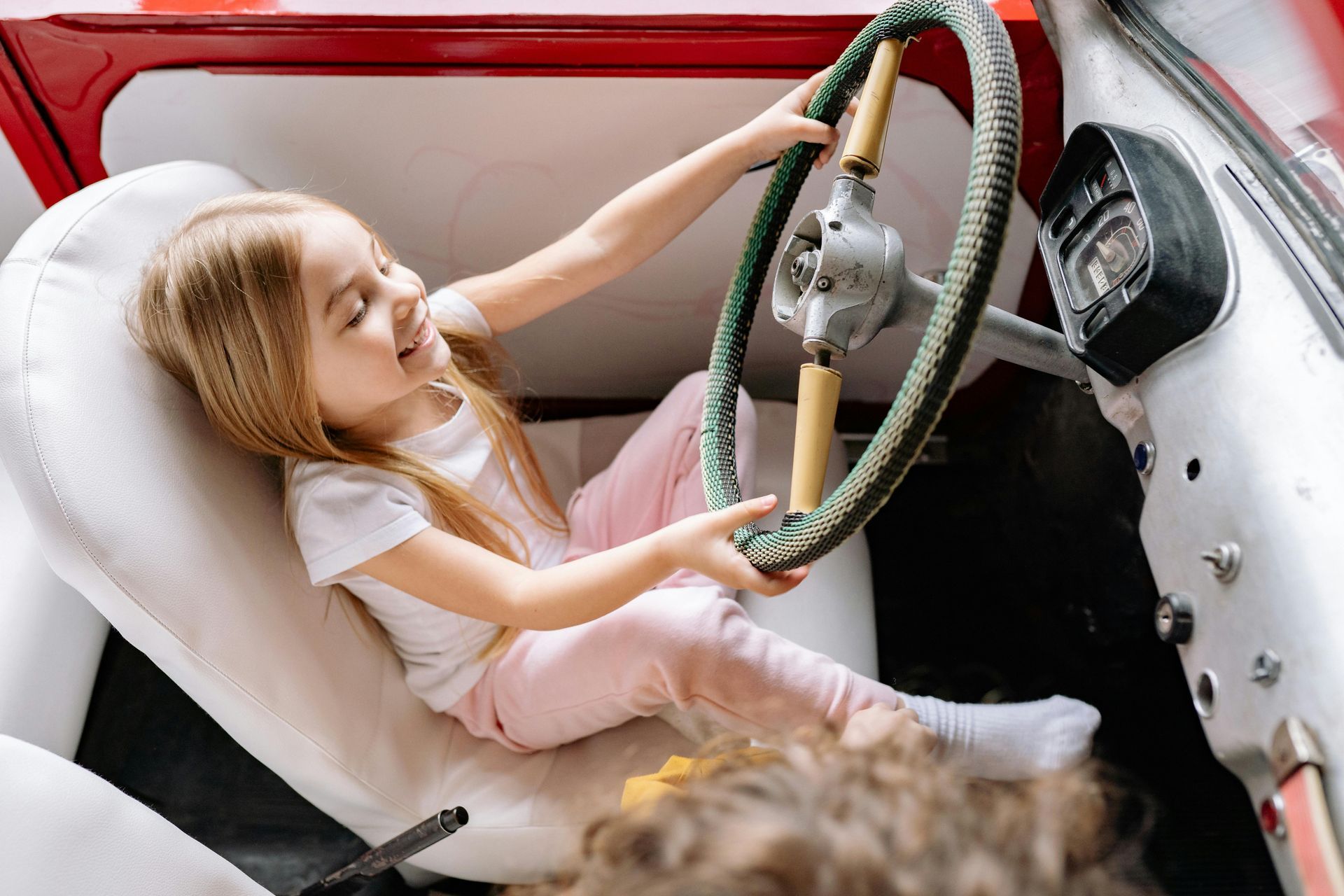 a young child sat in the drivers seat of a car pretending to steer it