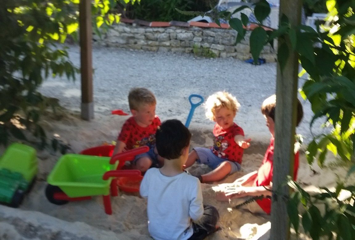 children sat in the shaded sandpit
