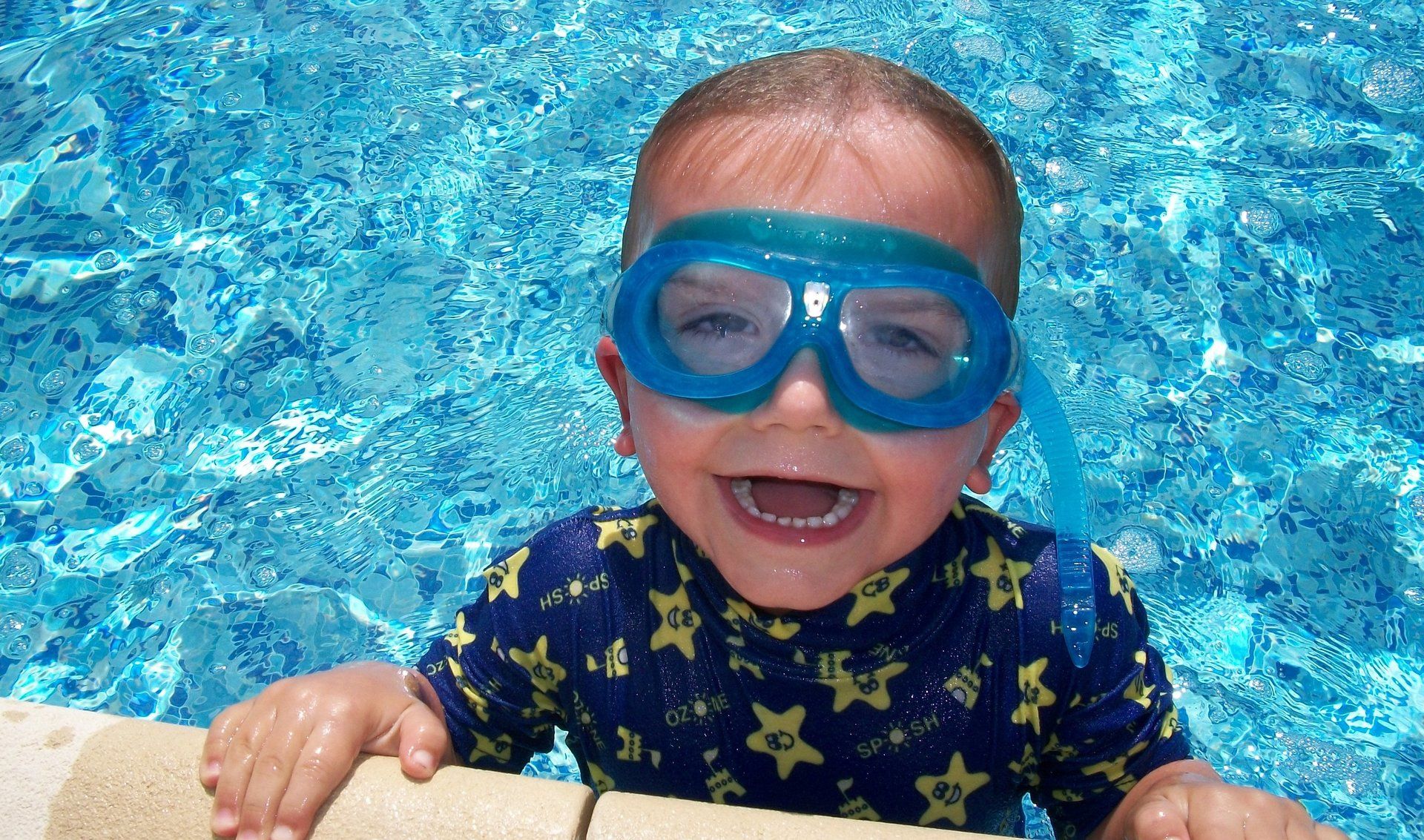 toddler with goggles in the pool