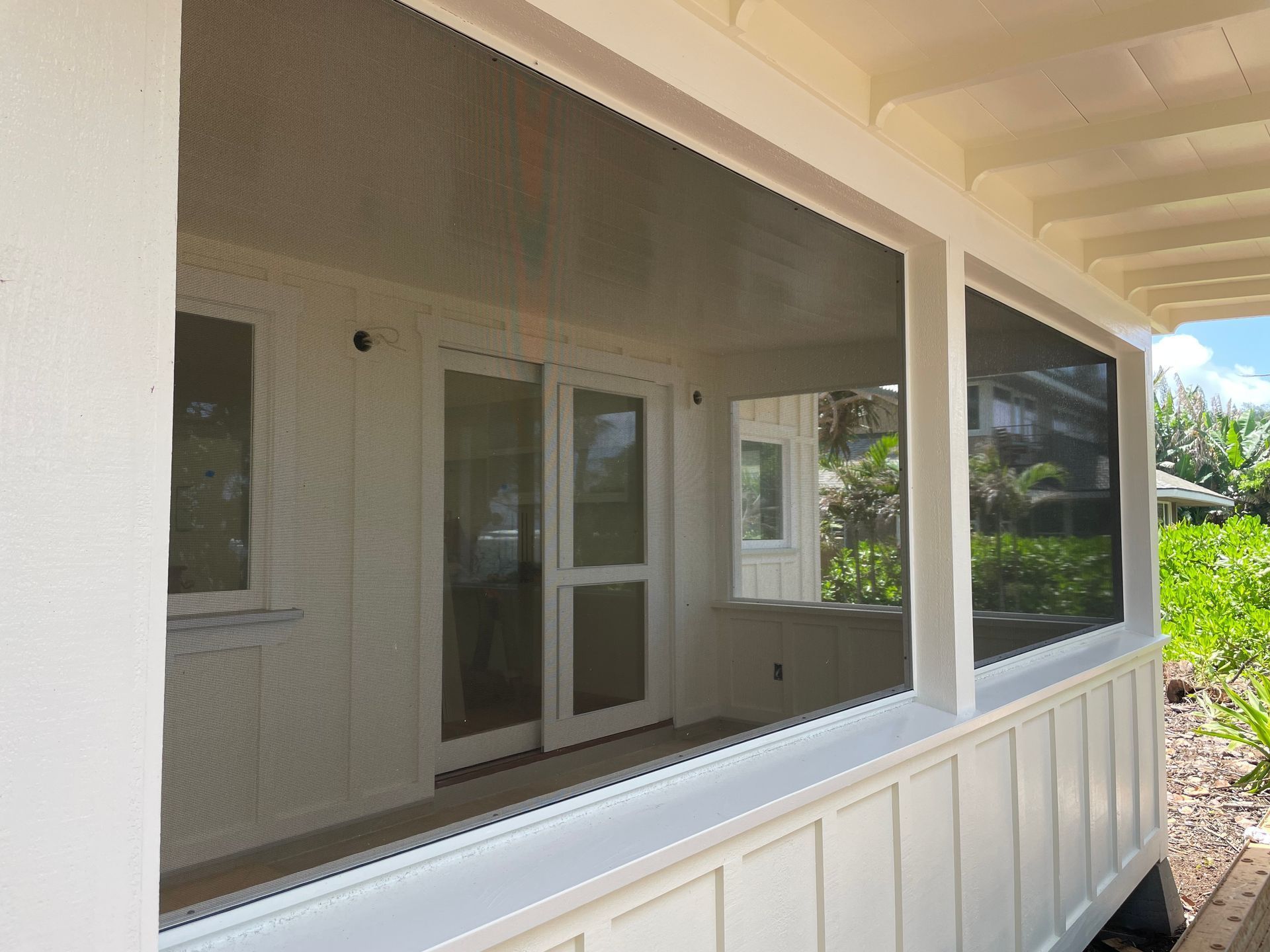 White screened porch with large windows, overlooking greenery.