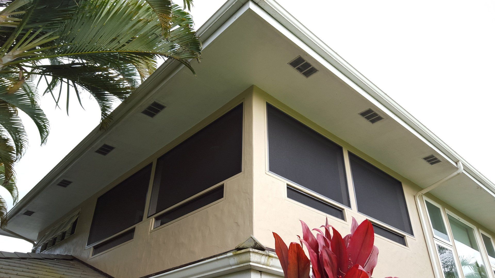 Beige building exterior with dark window screens, under a white overhang.