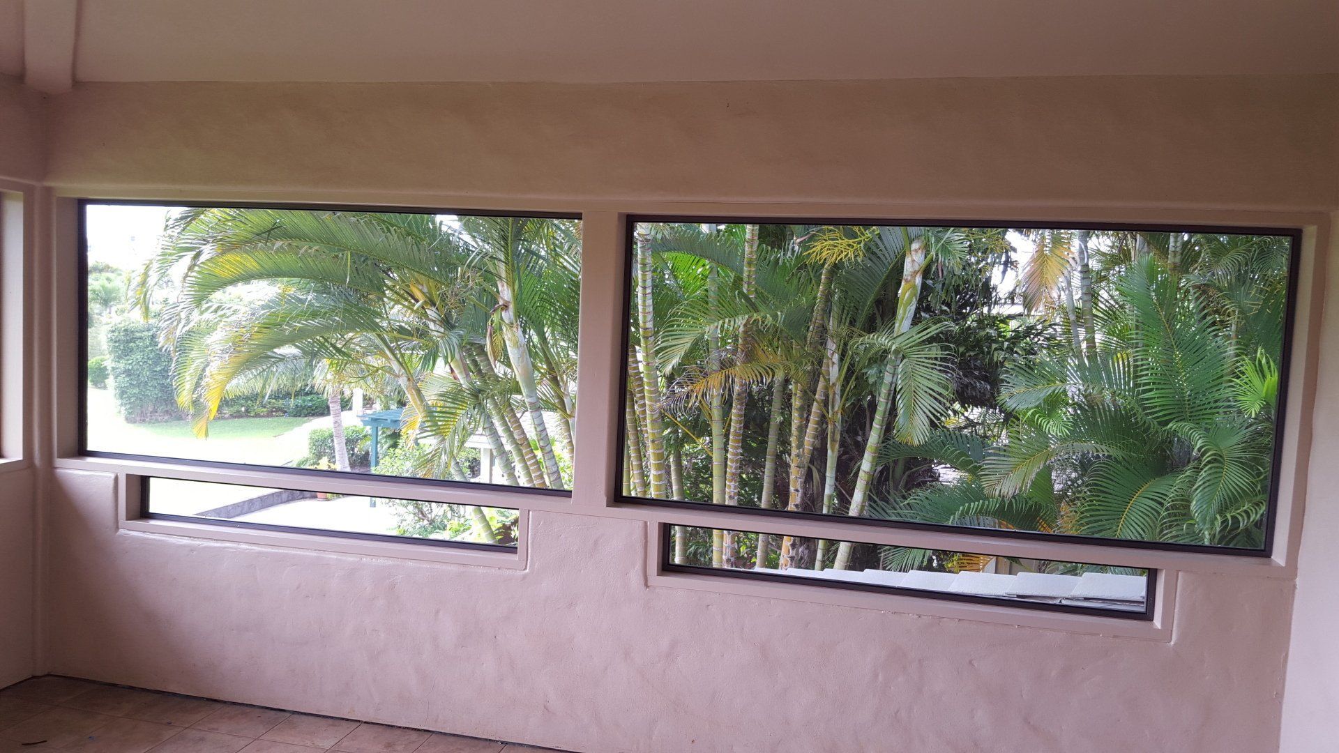 Two rectangular windows with a lush green outdoor view.