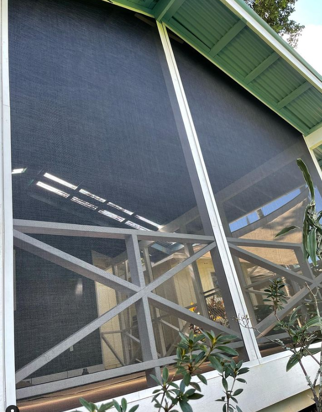 Screened porch with dark screens, white framing, and green roof.