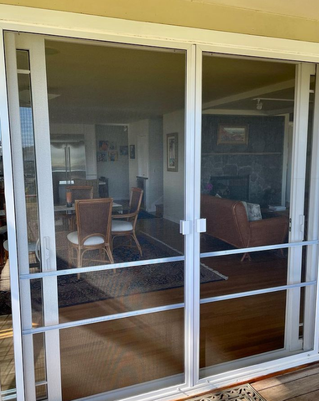 Sliding glass doors with white frames and safety bars, leading into a living room.