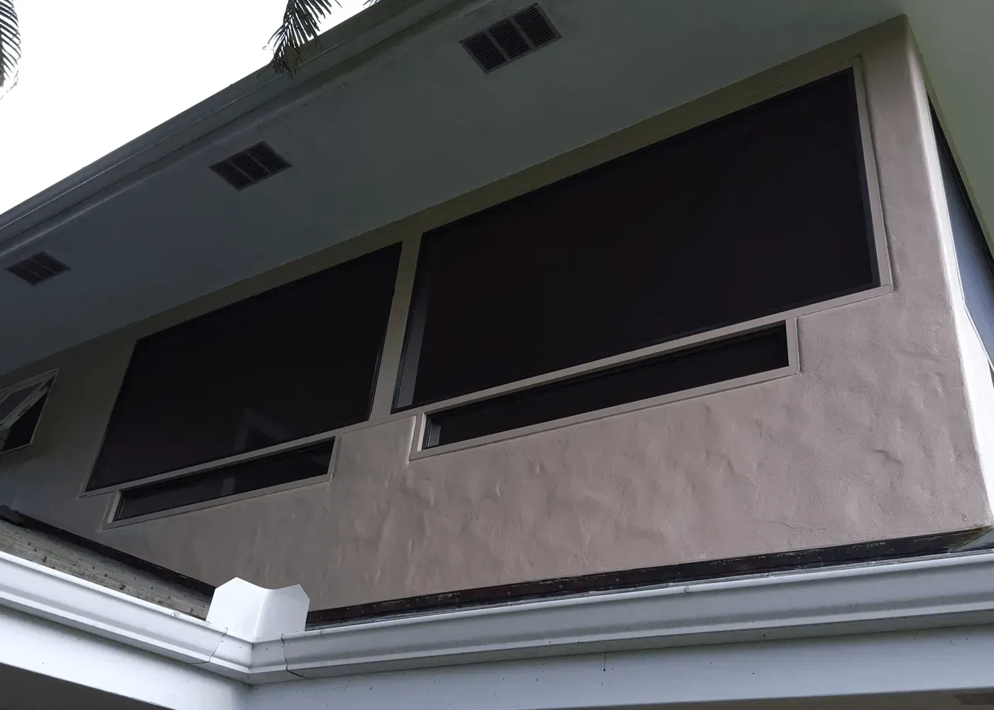 Exterior of a building with two large, dark sunshades and rectangular air vents.