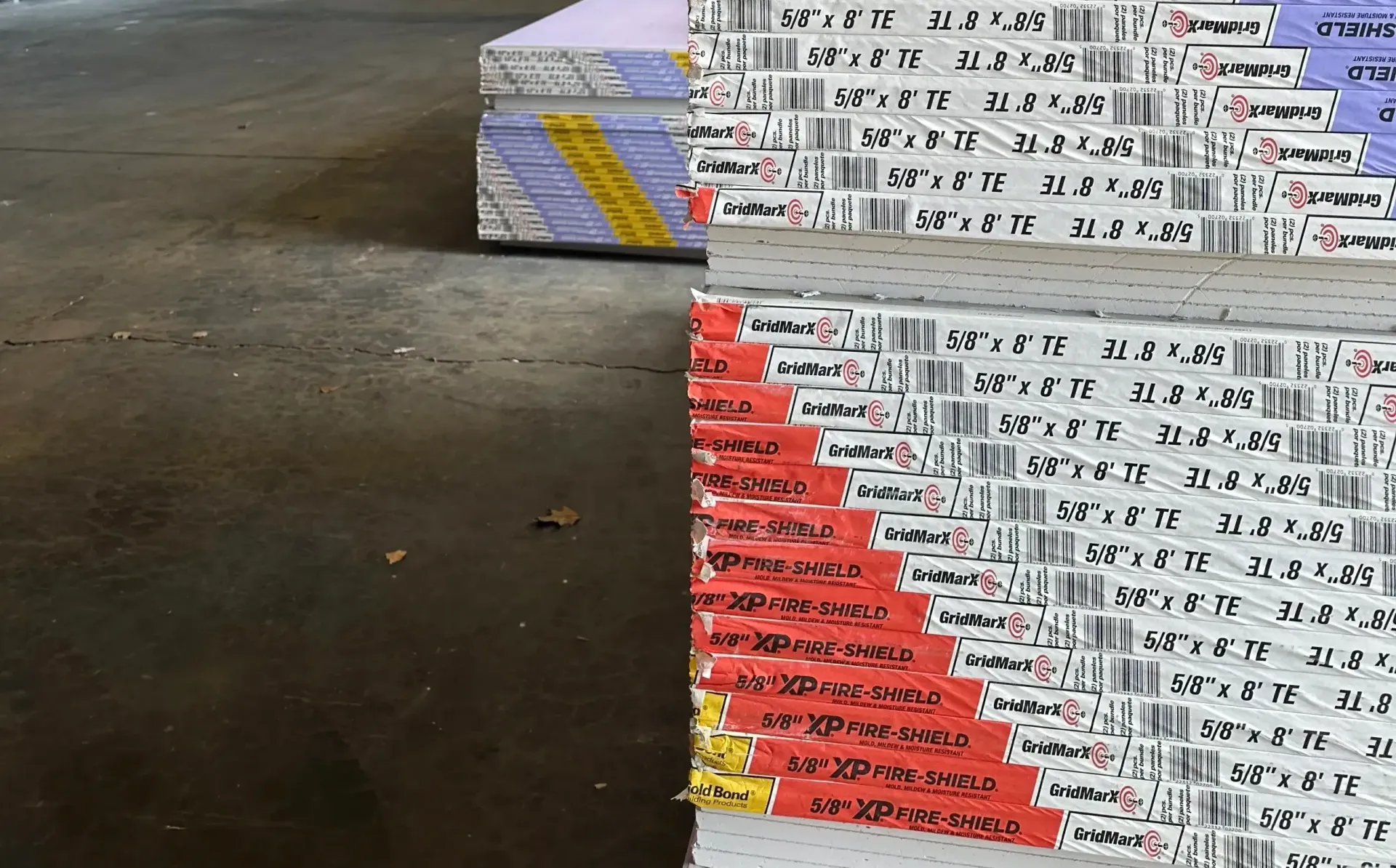 A stack of drywall sheets on a concrete floor.