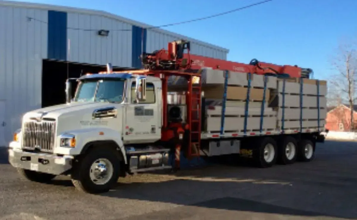 A white truck with a red crane on the back is parked in front of a building