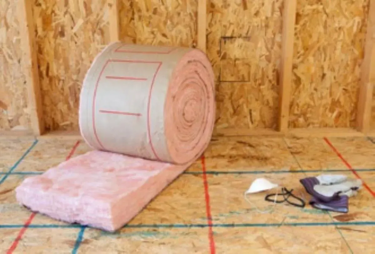 A roll of insulation is sitting on a wooden floor.