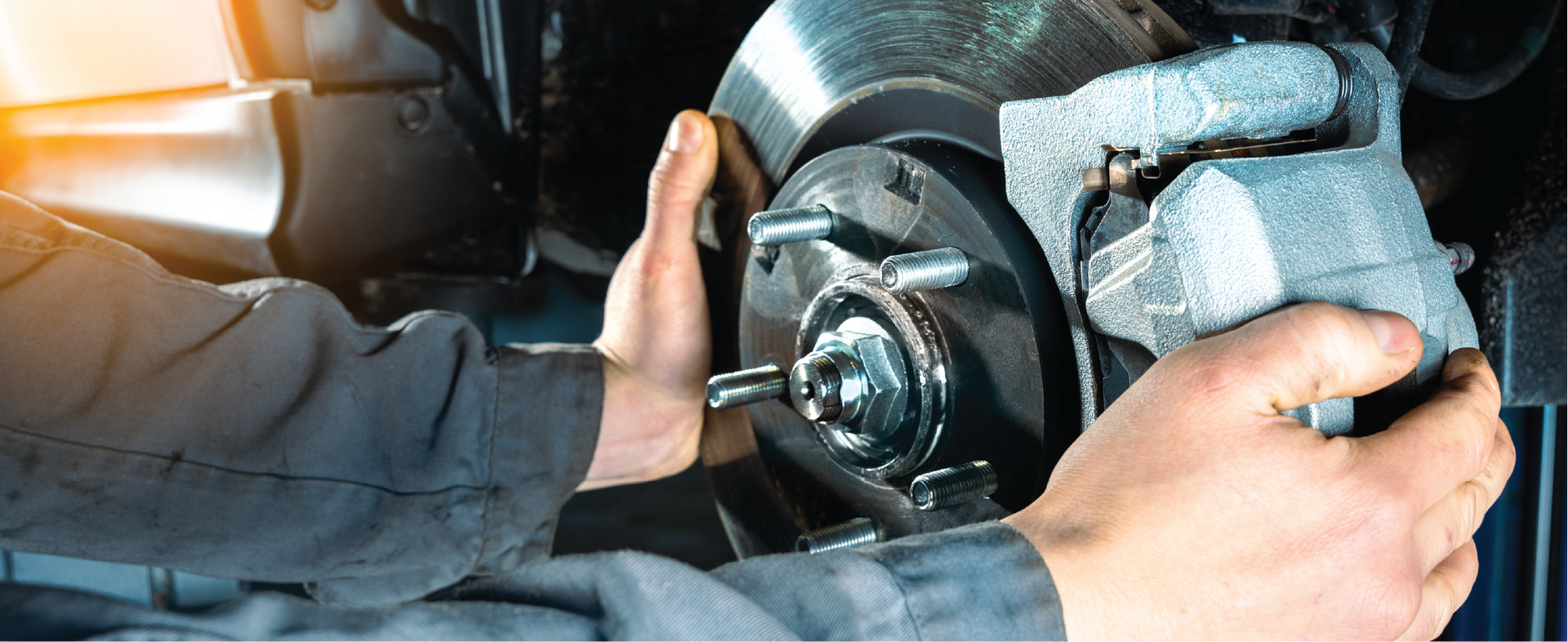 A man is fixing a brake on a car.