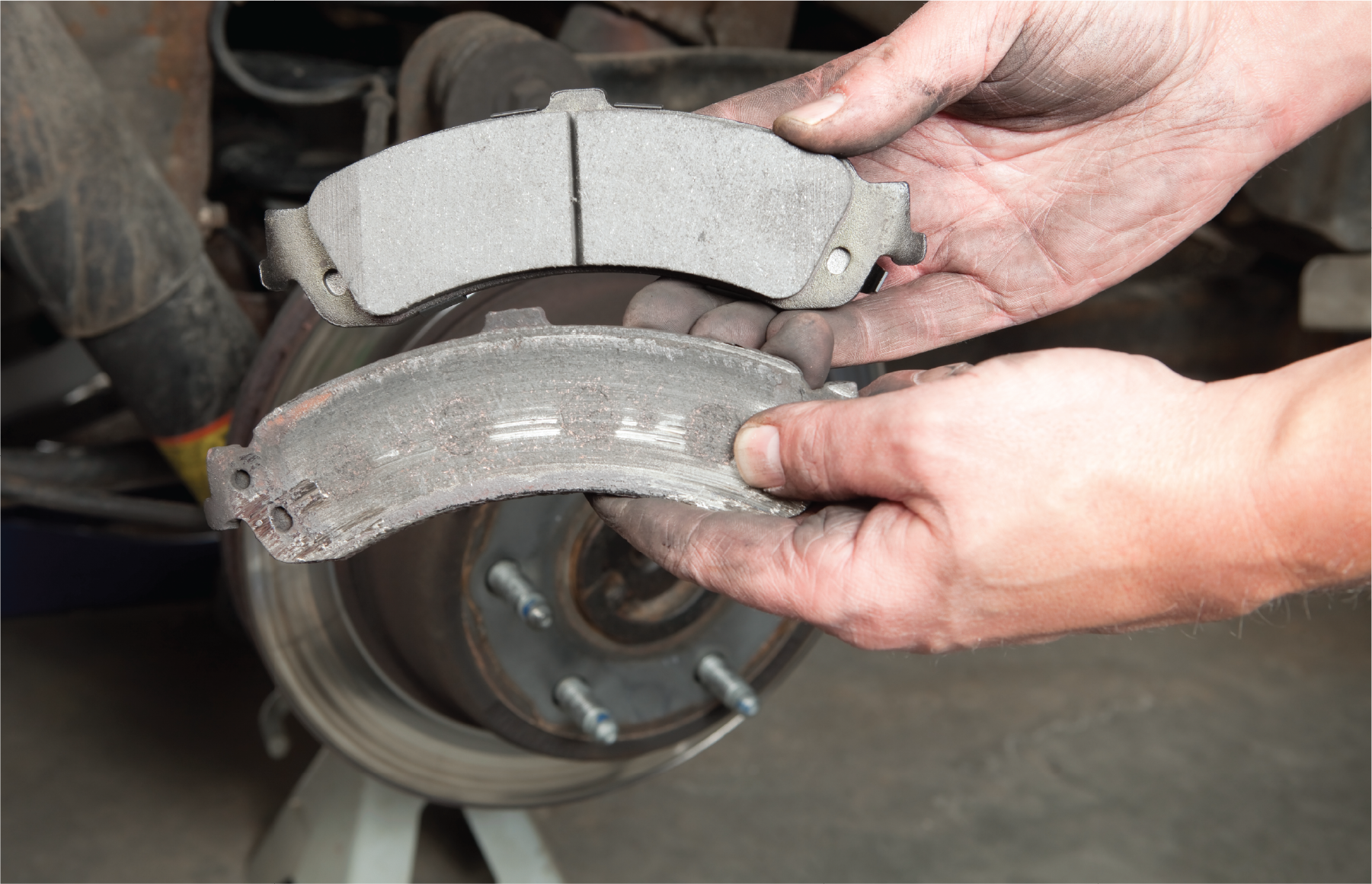 A person is holding a pair of brake pads in their hands.