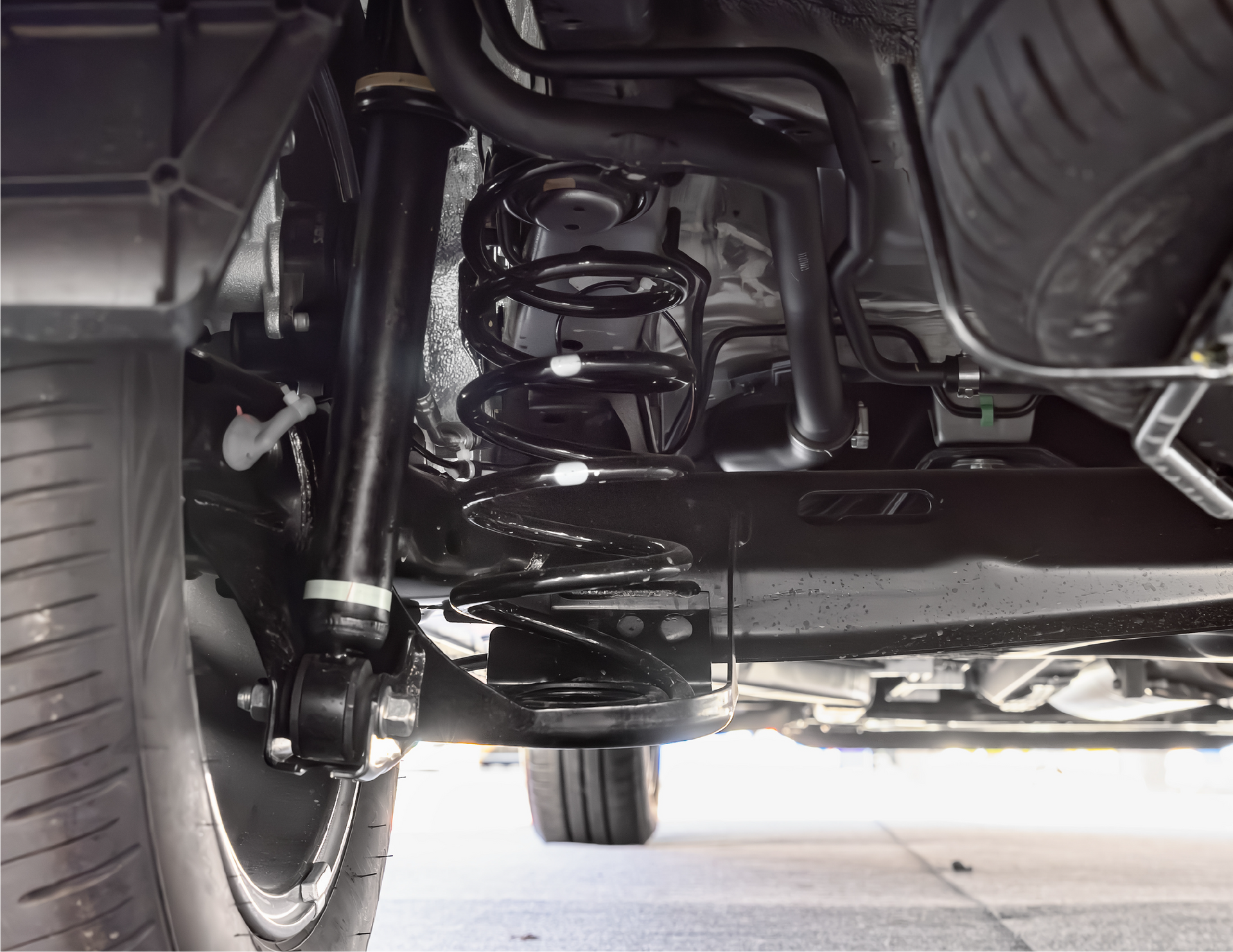 A close up of the underside of a car with shocks and a tire.