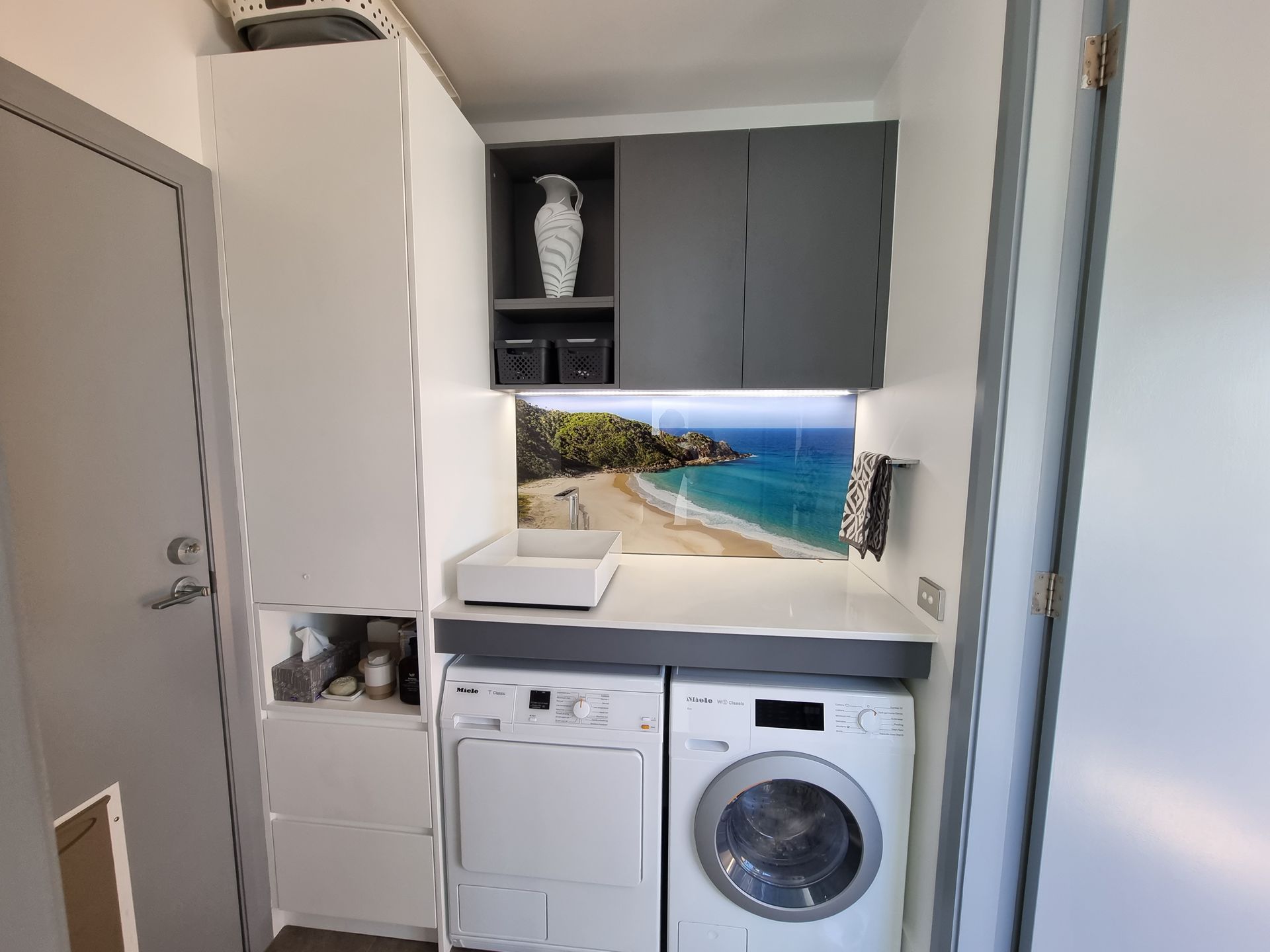 A Laundry Room with A Washer and Dryer and A Picture of A Beach on The Wall — L.L Projects in Harrington, NSW