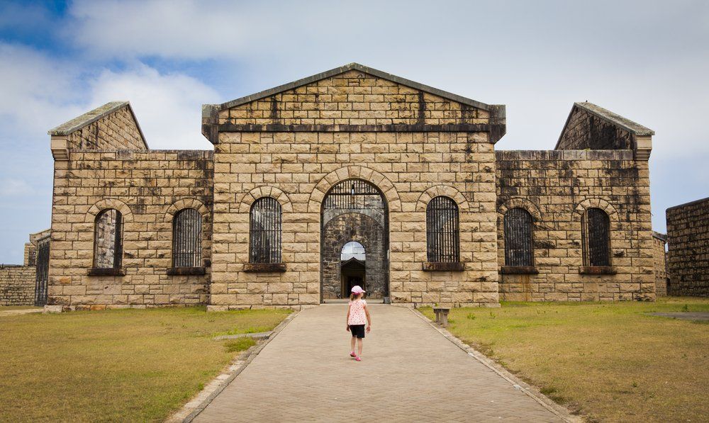 A Little Girl Is Walking in Front of A Large Brick Building — L.L Projects in Old Bar, NSW