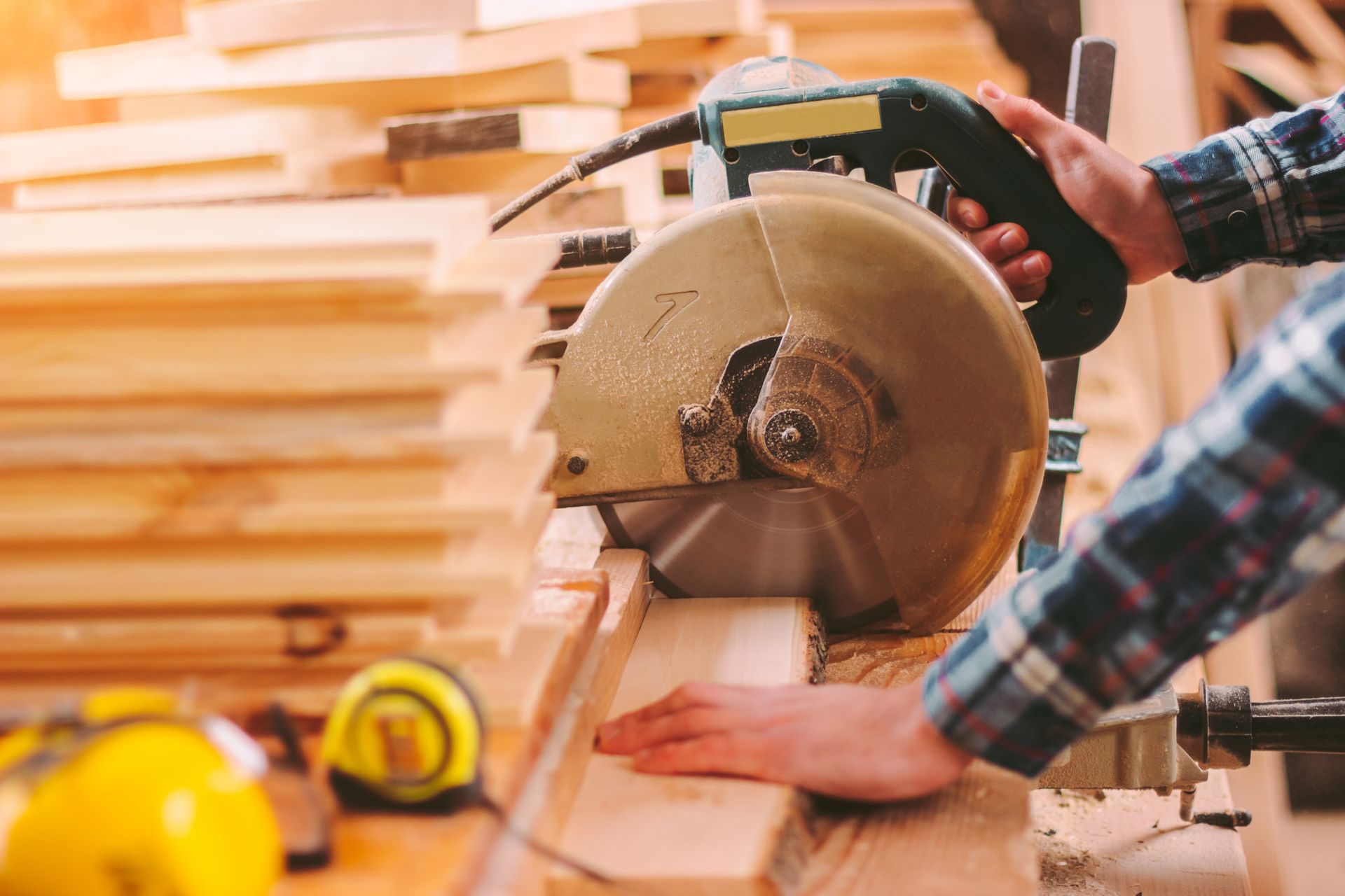 A man is using a circular saw to cut a piece of wood.