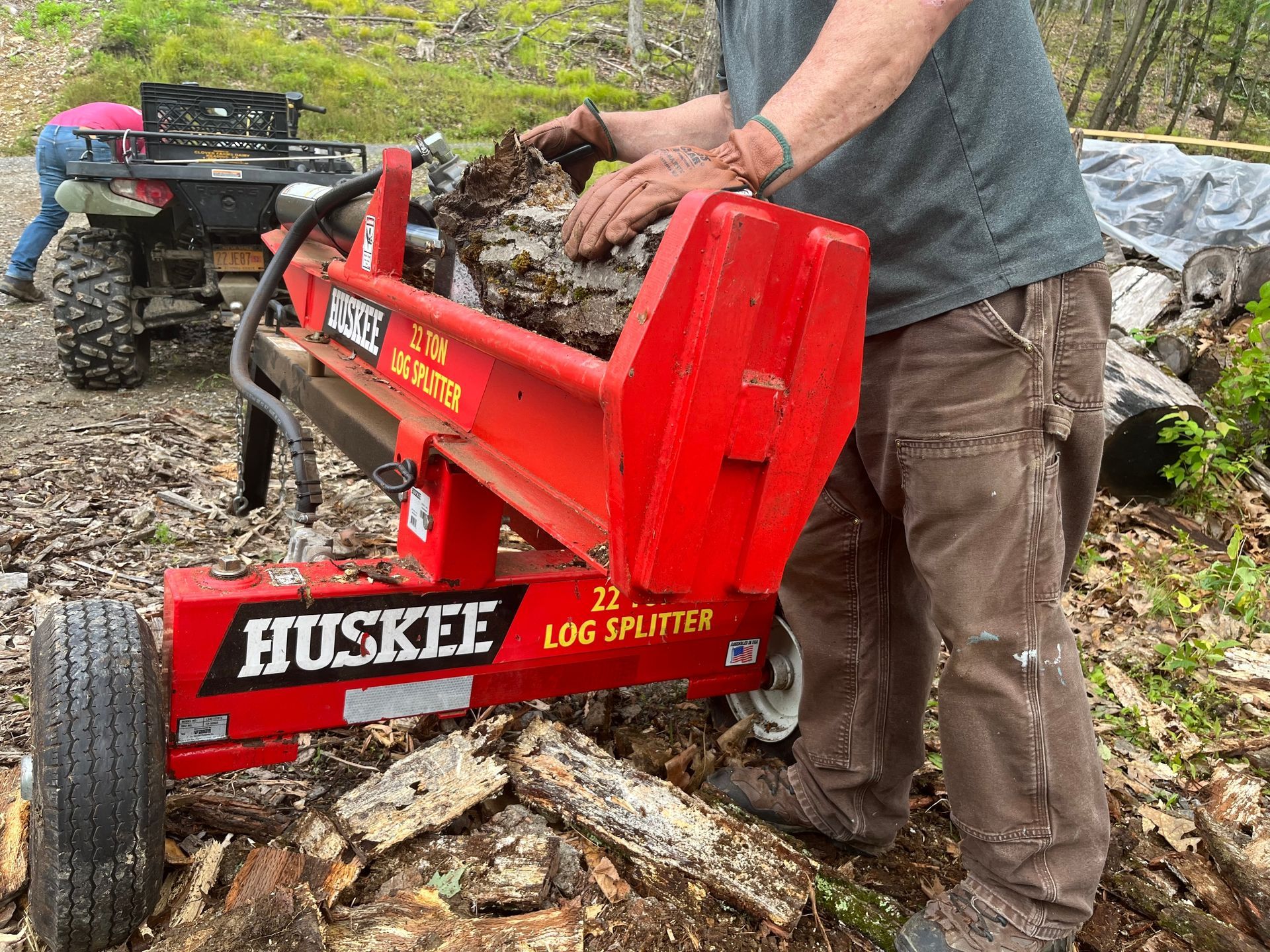 A man is using a huskee log splitter to split logs