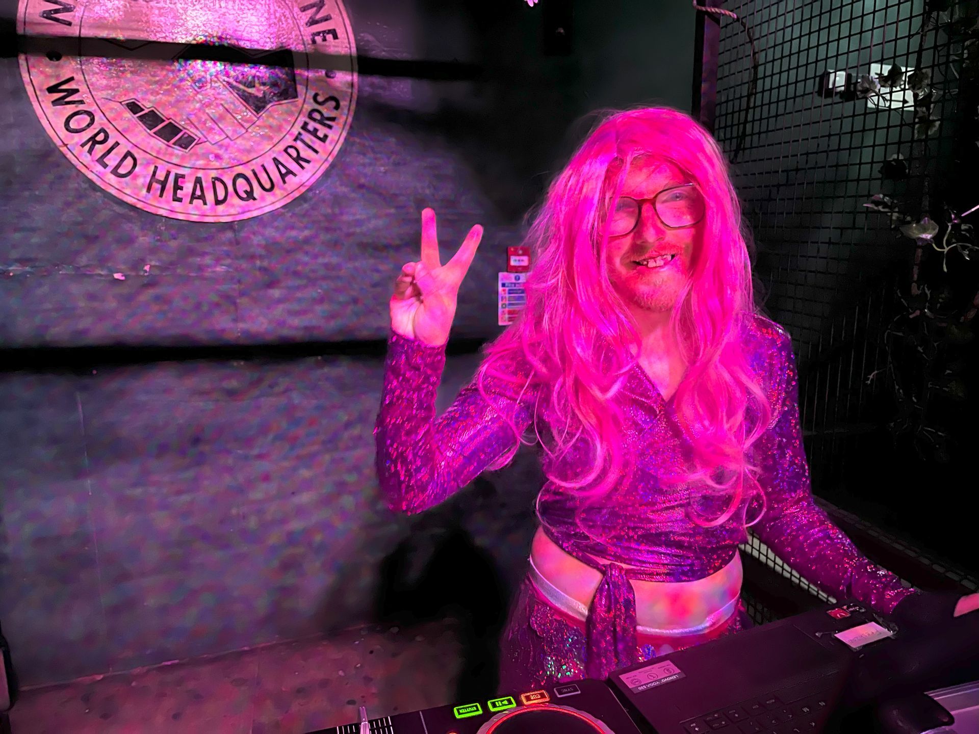 DJ with long pink hair gesturing a peace sign