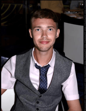 A photo of Ryan who is wearing a shirt, tie and waistcoat and is smiling.
