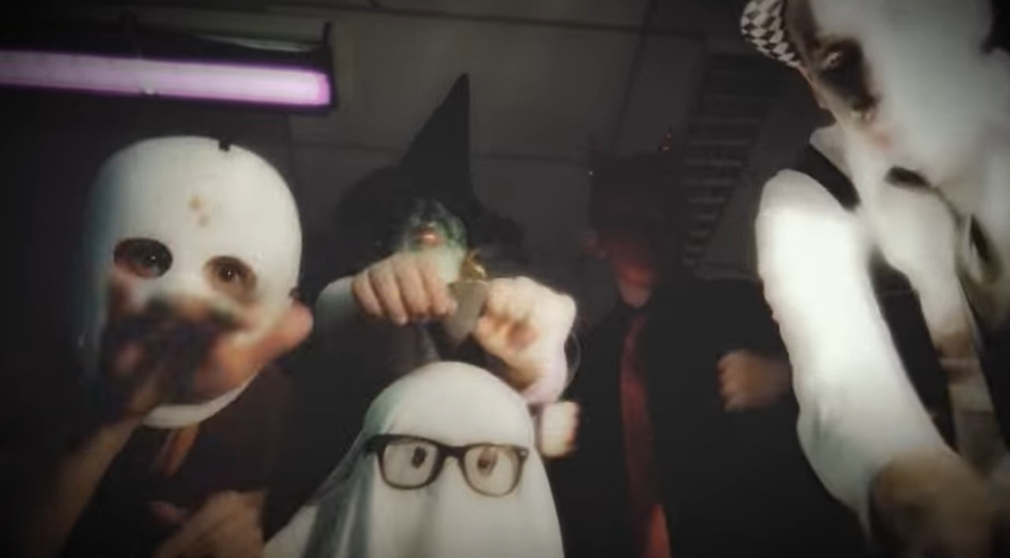 Still image from The Twist music video Love at Halloween. Group of adults dressed up for halloween