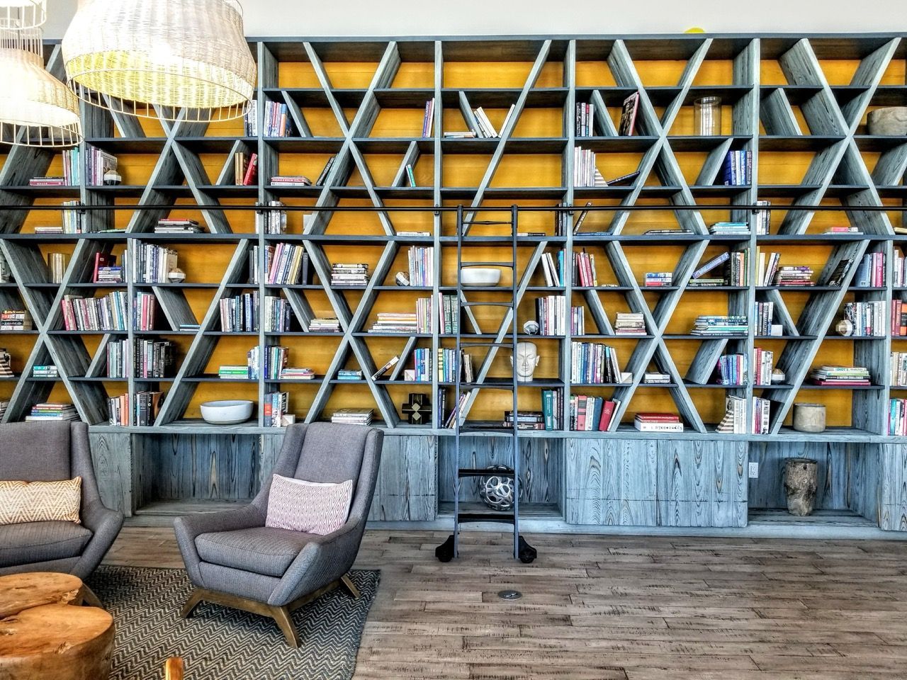 Interior lounge with a large geometric bookshelf, ladder, and seating.
