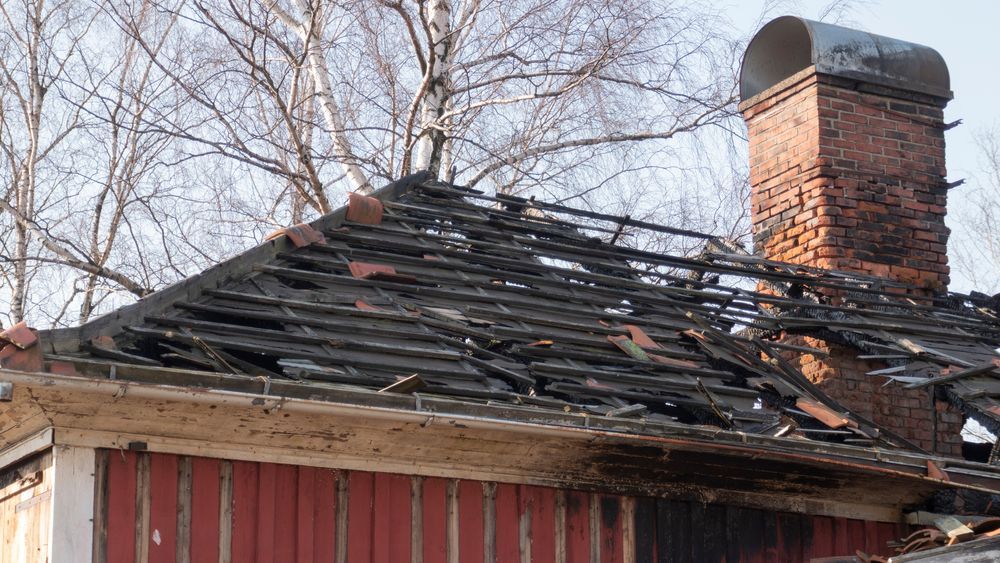 Burnt Roof of a Red Wooden House, With a Brick Chimney — CP Roofing in Old Bar, NSW