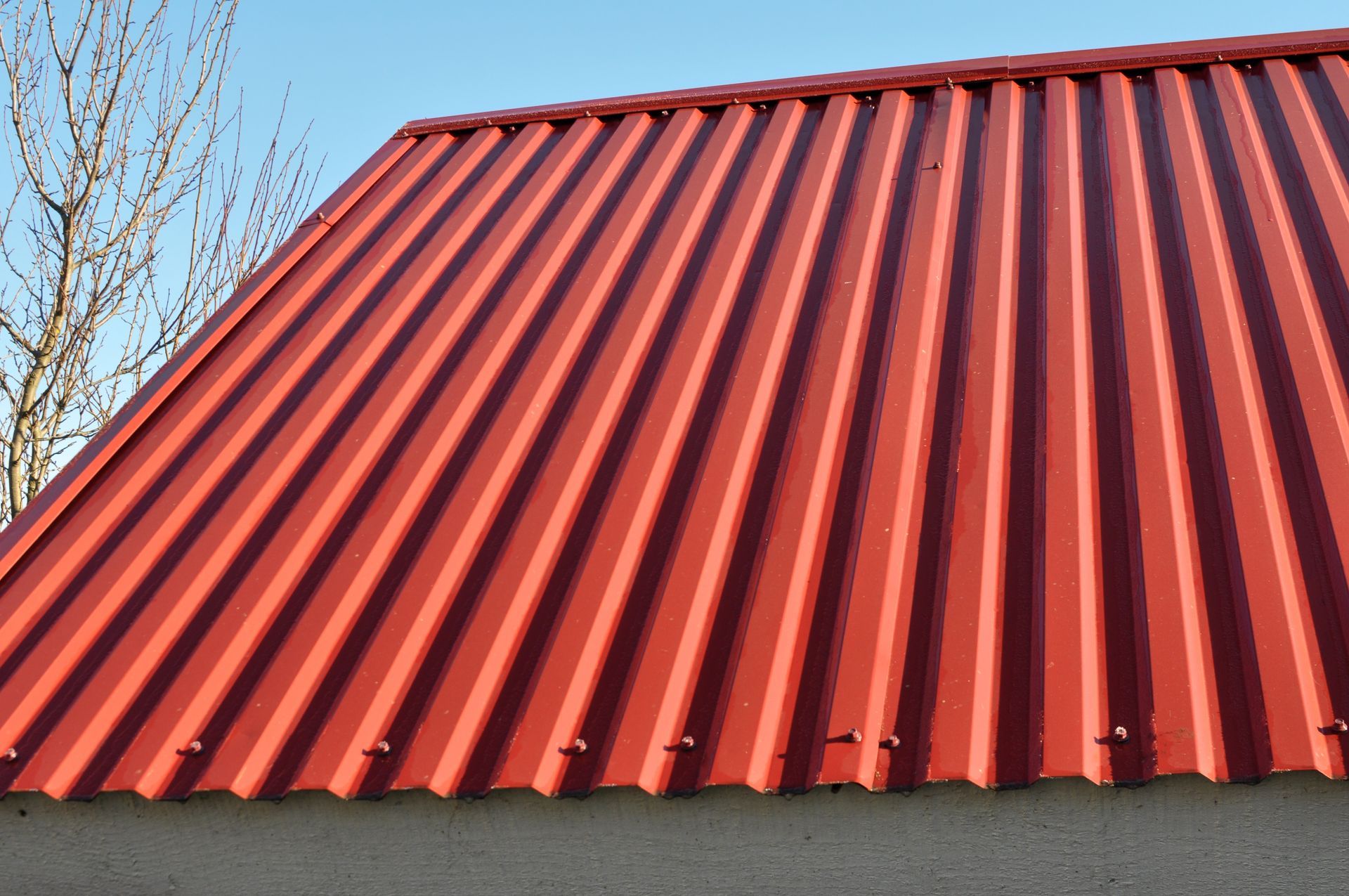 Red Corrugated Metal Roof of a Building Against a Blue Sky — CP Roofing in Old Bar, NSW