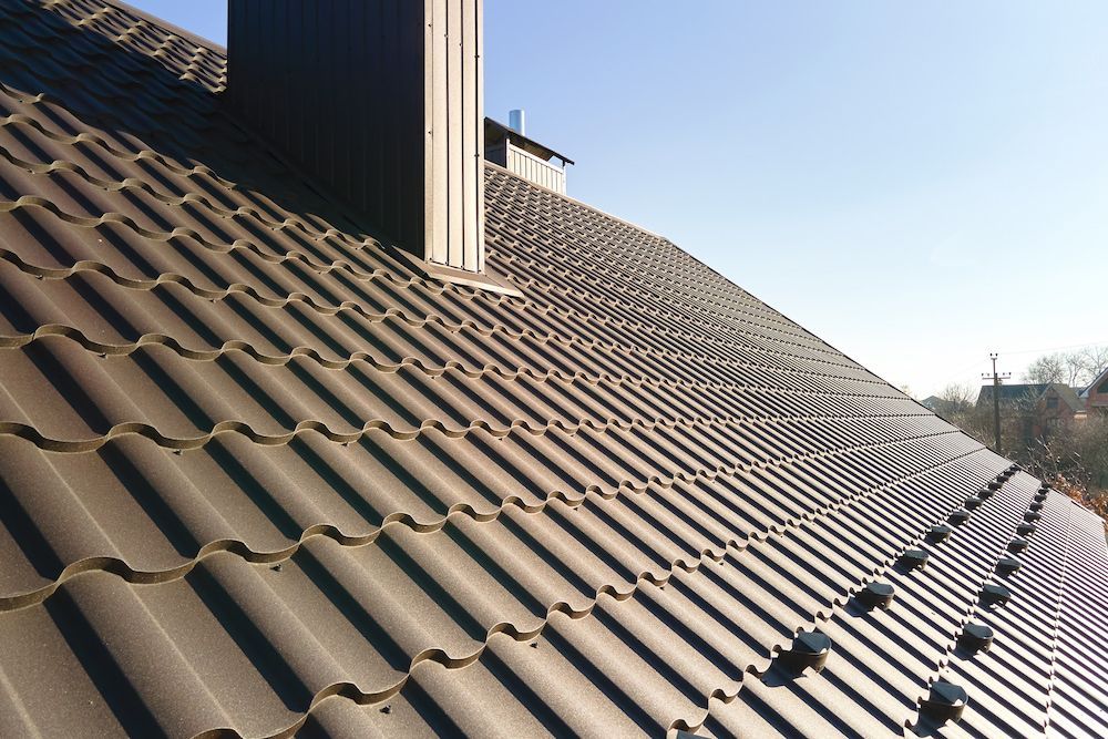 Brown Metal Tile Roof With a Chimney Against a Blue Sky — CP Roofing in Old Bar, NSW