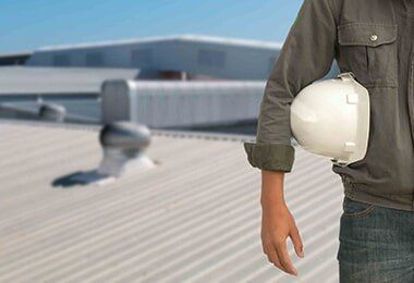 A Man Wearing A Hard Hat Is Standing On A Roof — CP Roofing in Old Bar, NSW