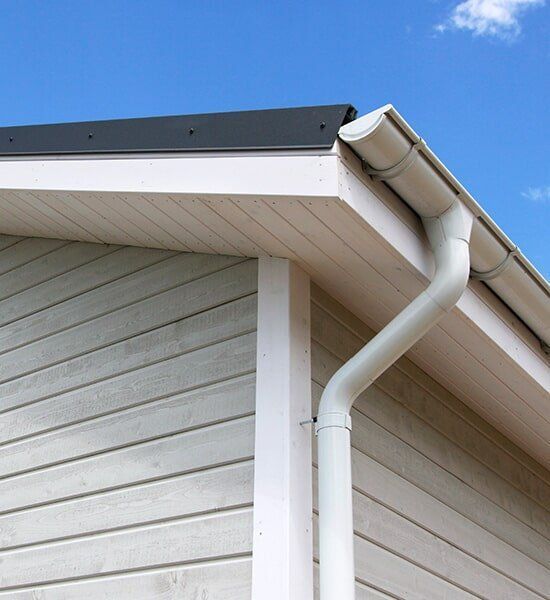 A White Gutter Is Attached To The Side Of A House — CP Roofing in Old Bar, NSW