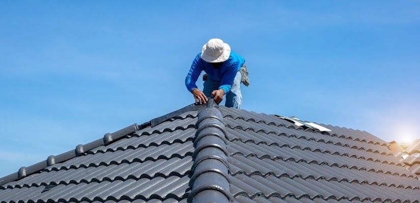 A Man Is Working On The Roof Of A House — CP Roofing in Old Bar, NSW