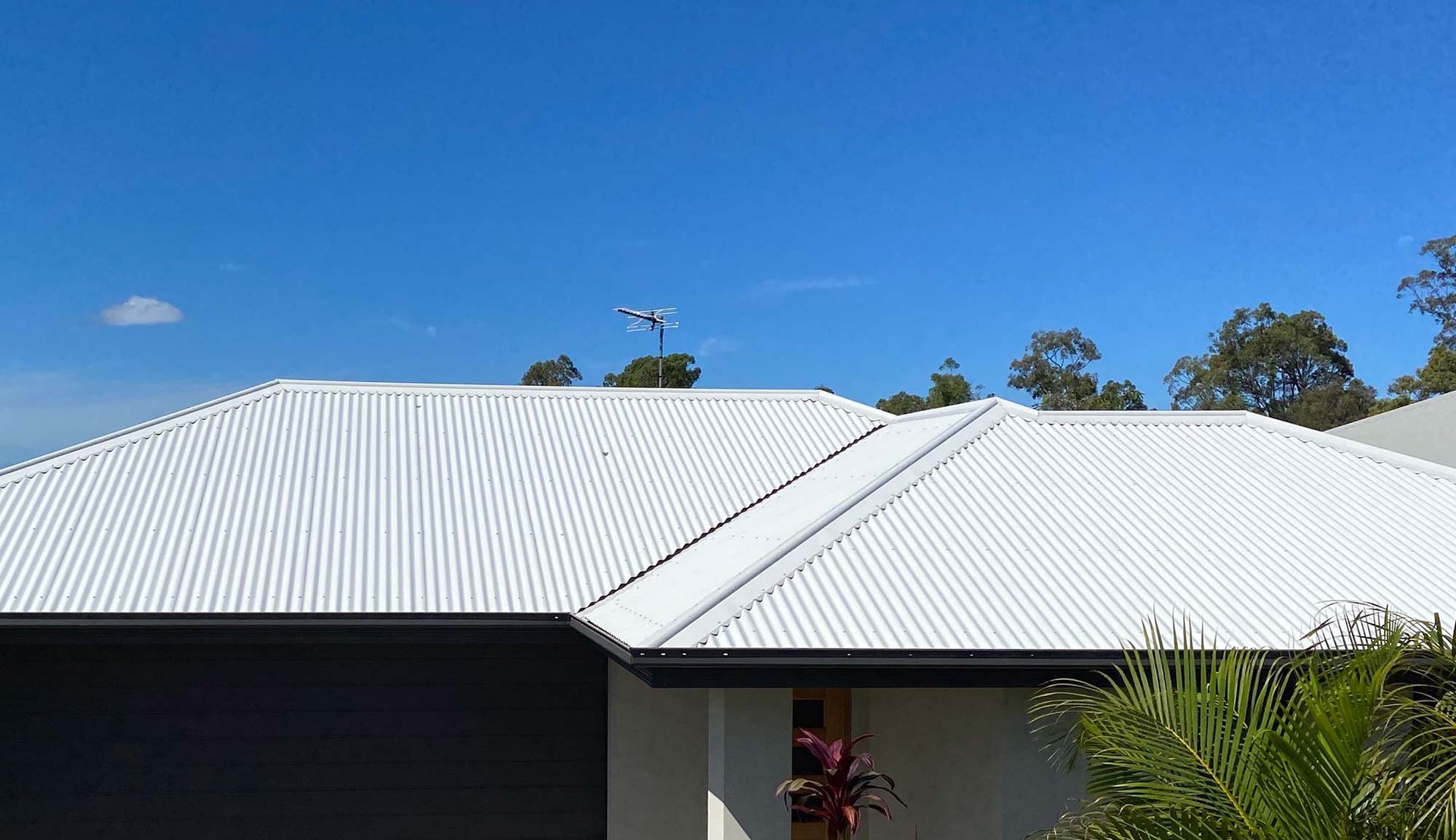 A House With A White Roof And A Blue Sky In The Background — CP Roofing in Wingham, NSW