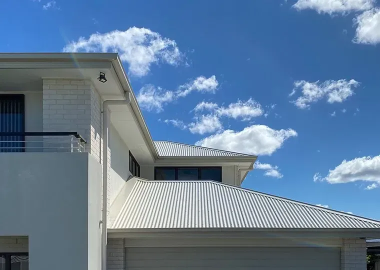 A White House With A White Roof And A Blue Sky In The Background — CP Roofing in Wingham, NSW