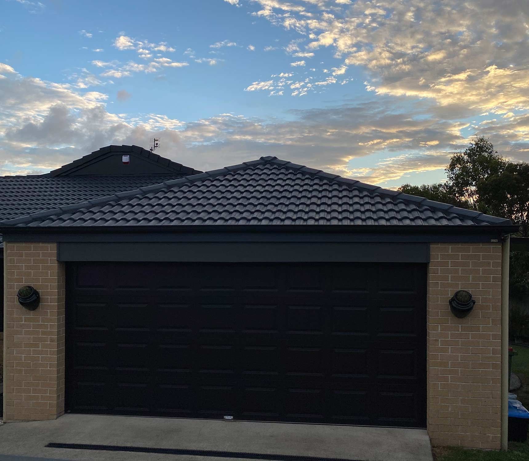 A House With A Black Garage Door And A Blue Roof — CP Roofing in Taree, NSW