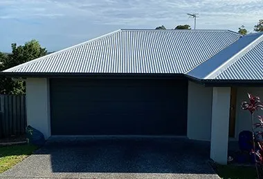 White House With a Black Garage Door and a White Roof — CP Roofing in Old Bar, NSW
