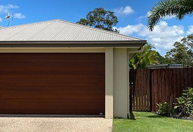 House With a Garage Door and a Wooden Fence in Front of It — CP Roofing in Old Bar, NSW