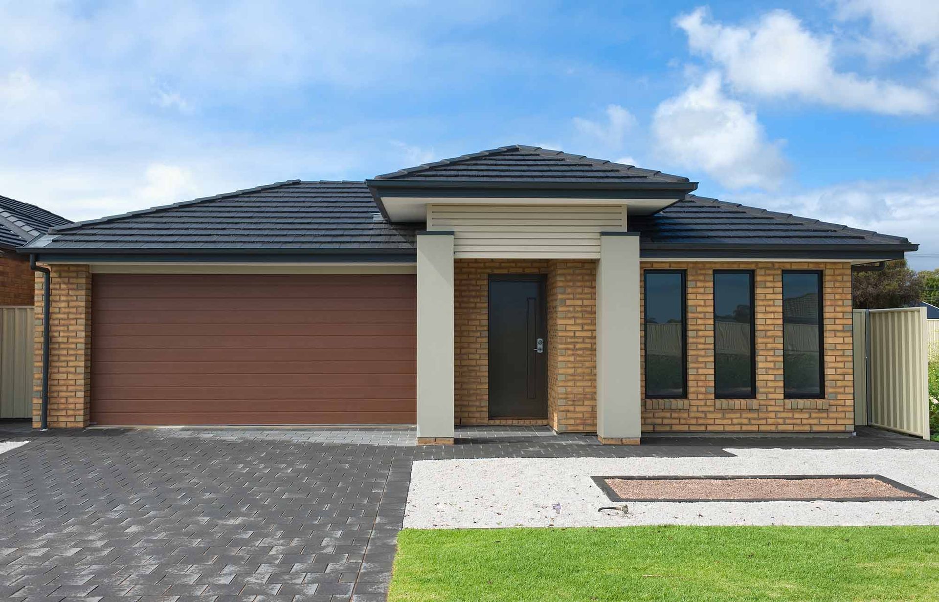 A Brick House With A Garage And A Driveway — CP Roofing in Harrington, NSW