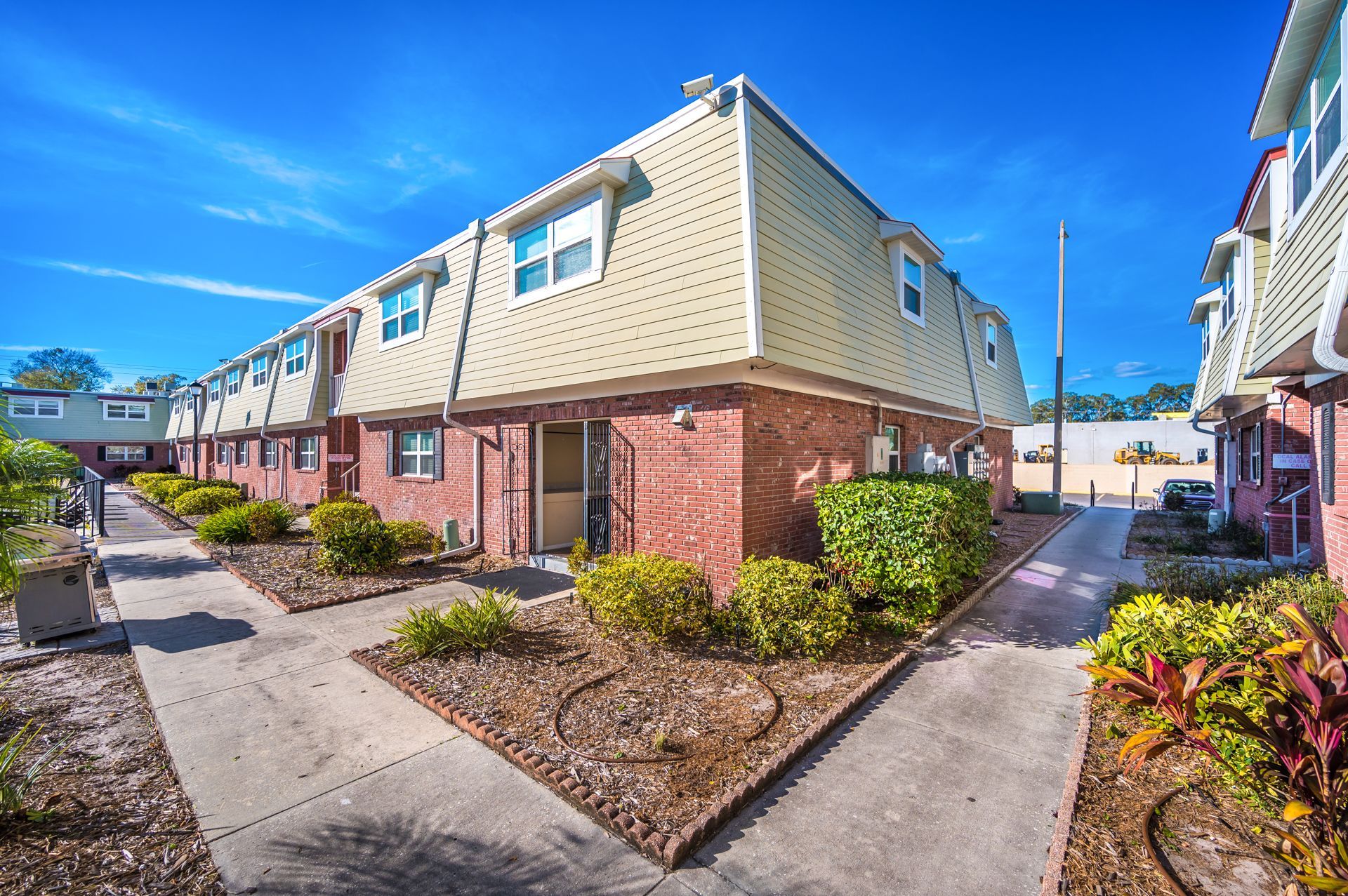 Row of townhouses with brick exteriors and tan upper levels, blue sky.