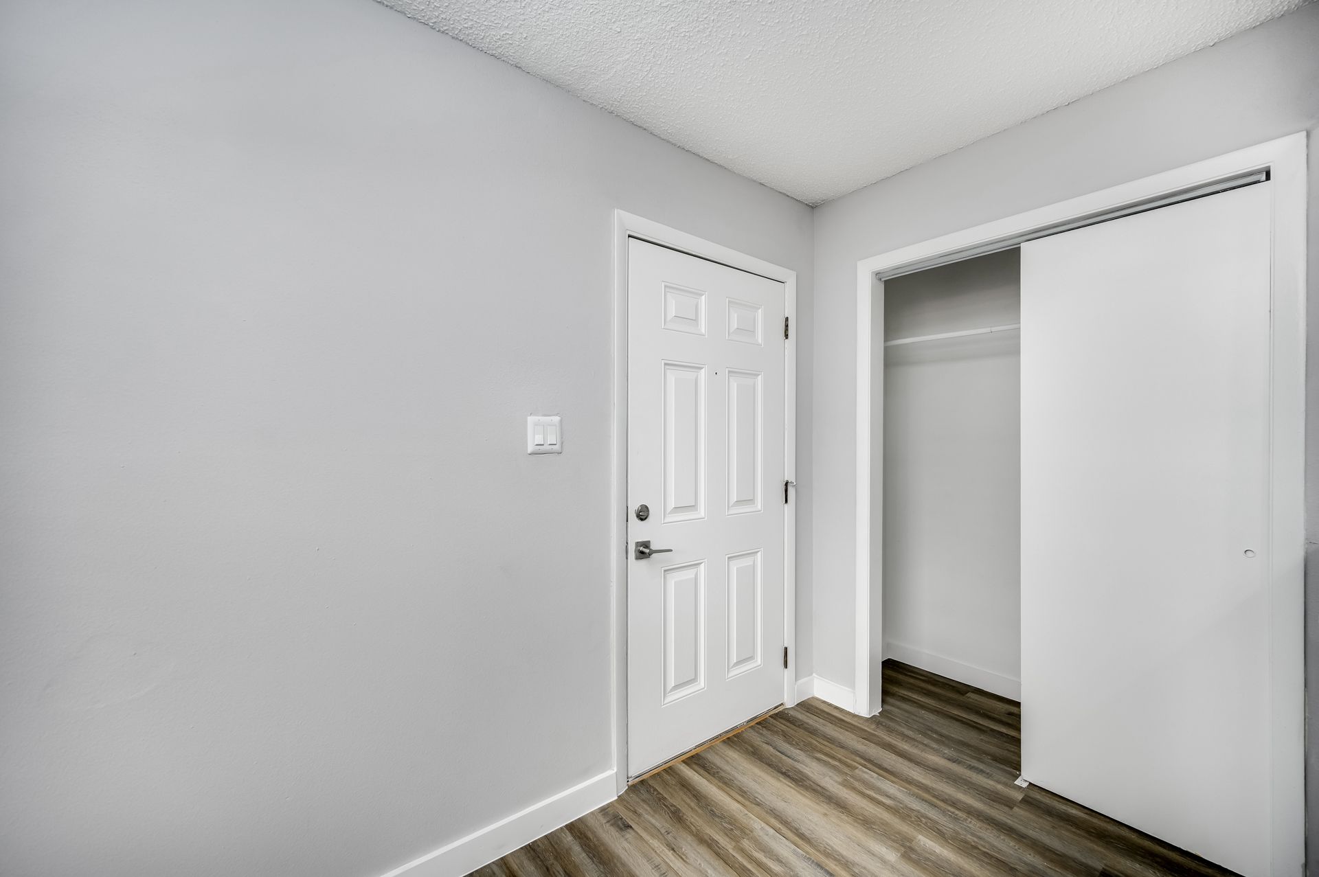 Empty room with light gray walls, white trim, and a closet.