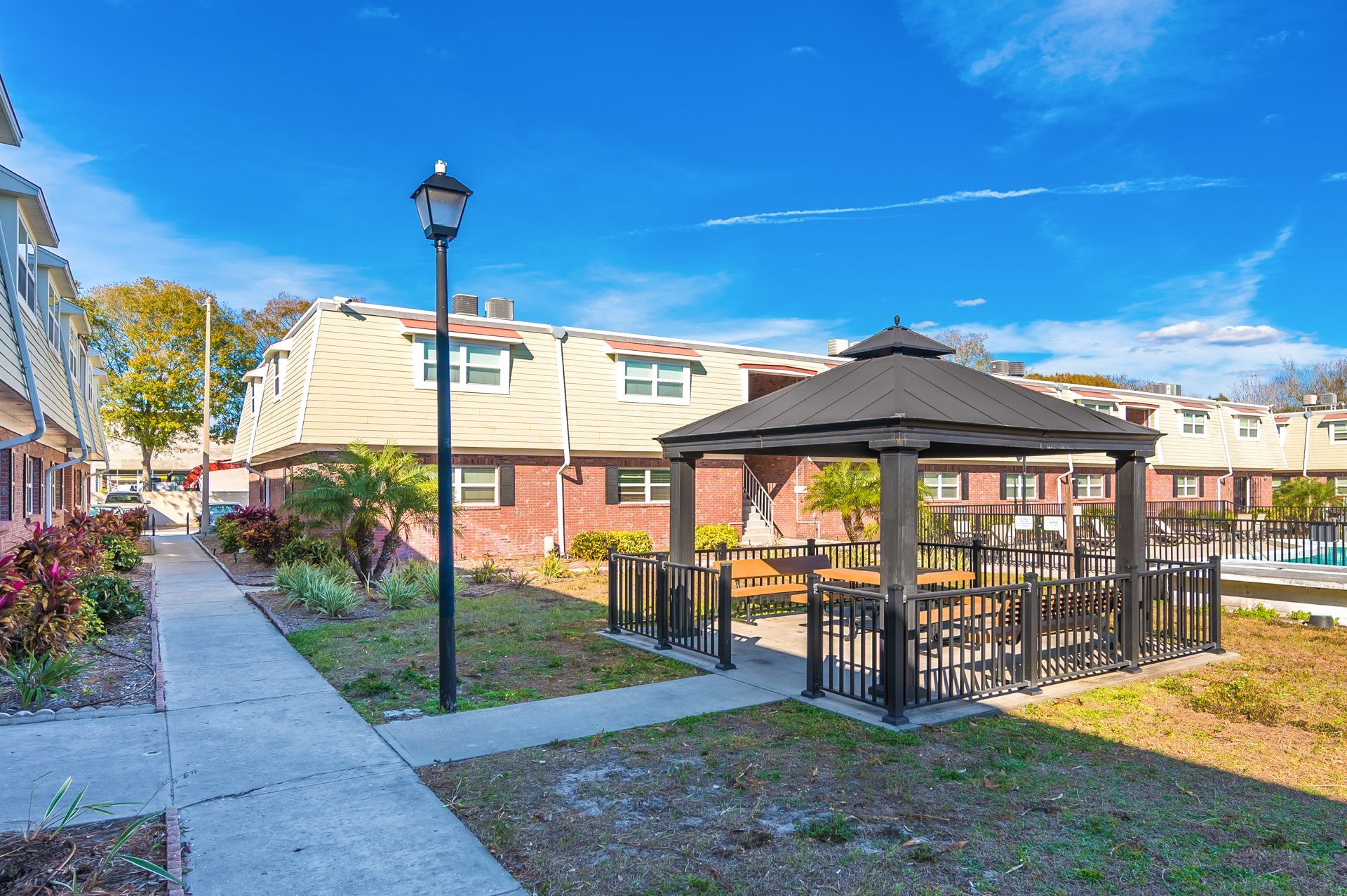 Townhouses with a gazebo and sidewalk on a sunny day.