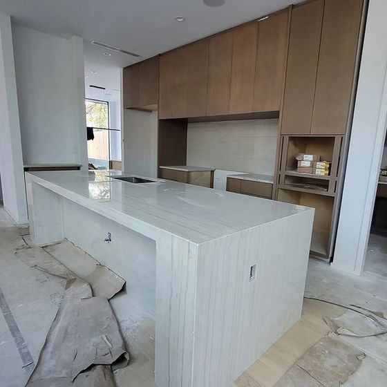 A kitchen with a large white counter top and wooden cabinets.