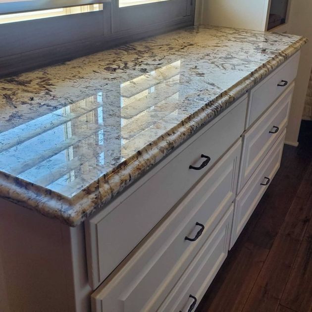 A white cabinet with a granite counter top in a kitchen.